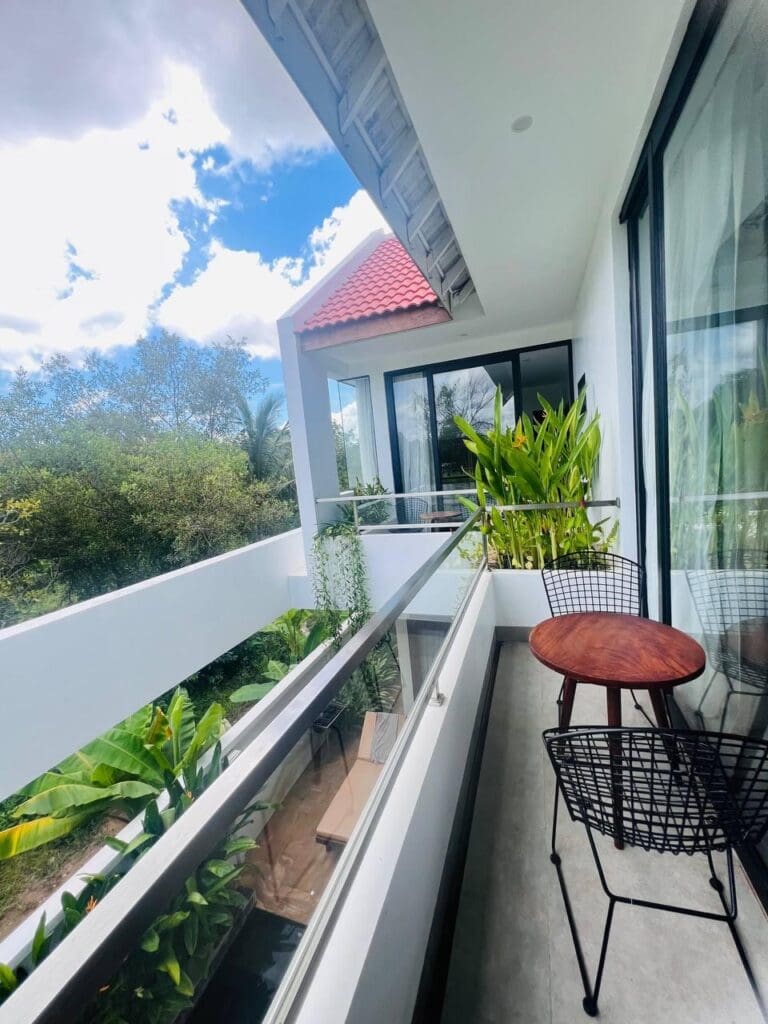 Balcon spacieux d'une villa de 3 chambres à Siem Reap avec une végétation luxuriante et des sièges extérieurs confortables